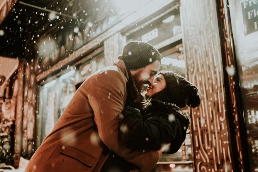 Un couple qui s'enlace sous une chute de neige.