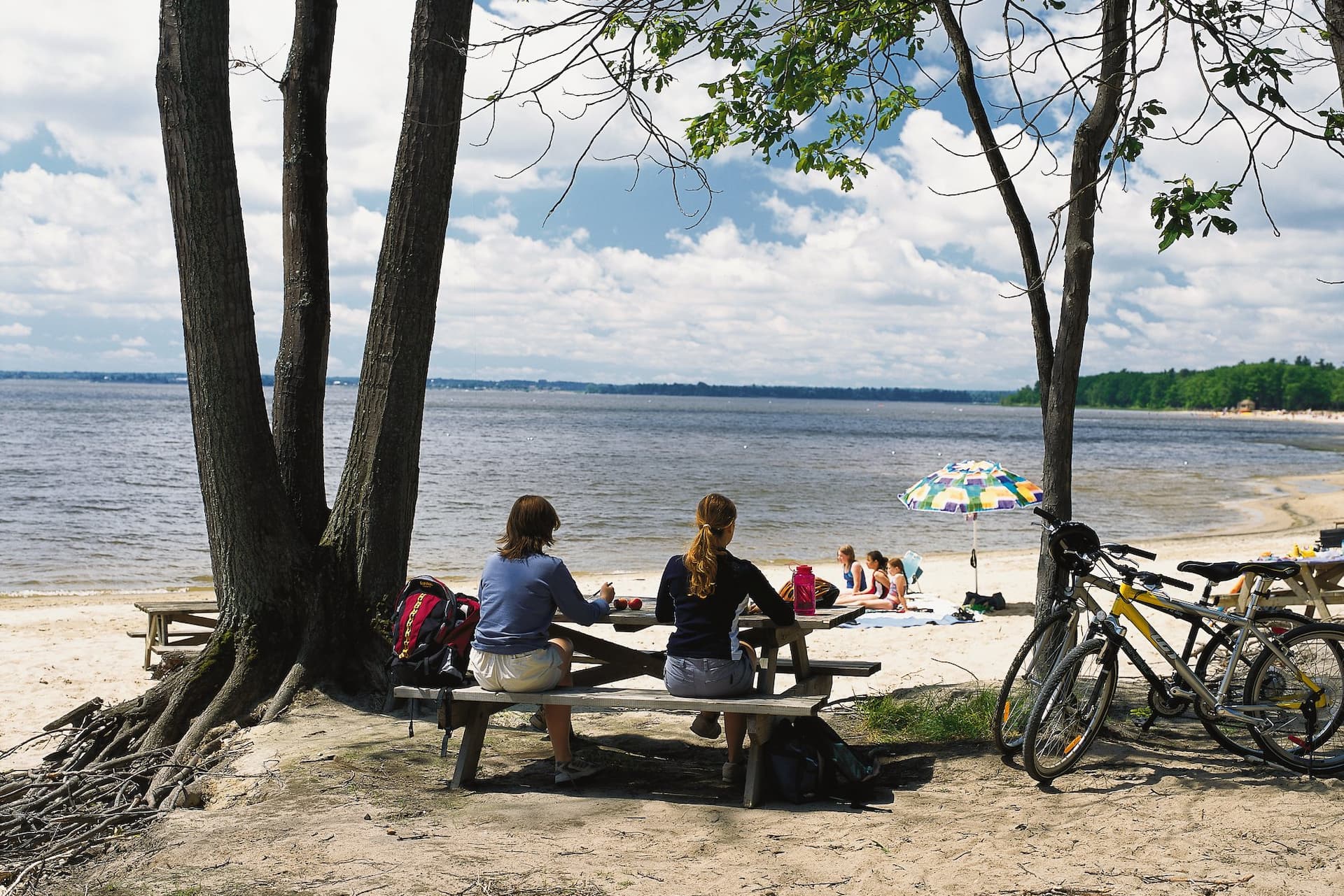 Deux personnes font un pique-nique sur le bord du lac des Deux-Montagnes leurs vélos à côté