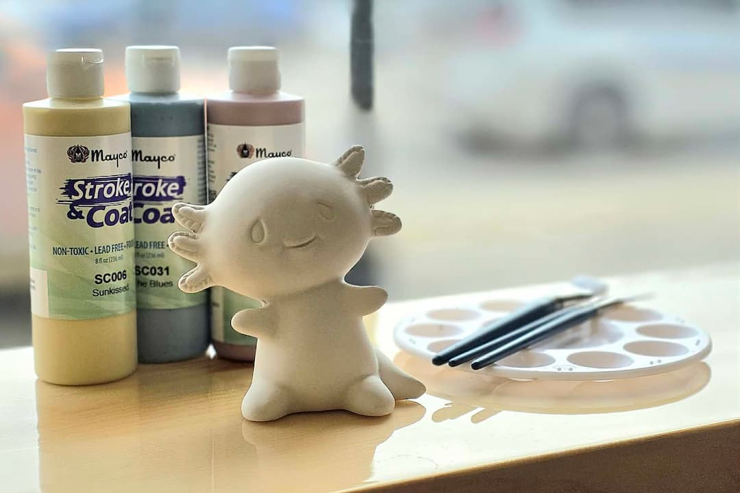 Petite statue de poterie avec des tubes de peinture et des pinceaux