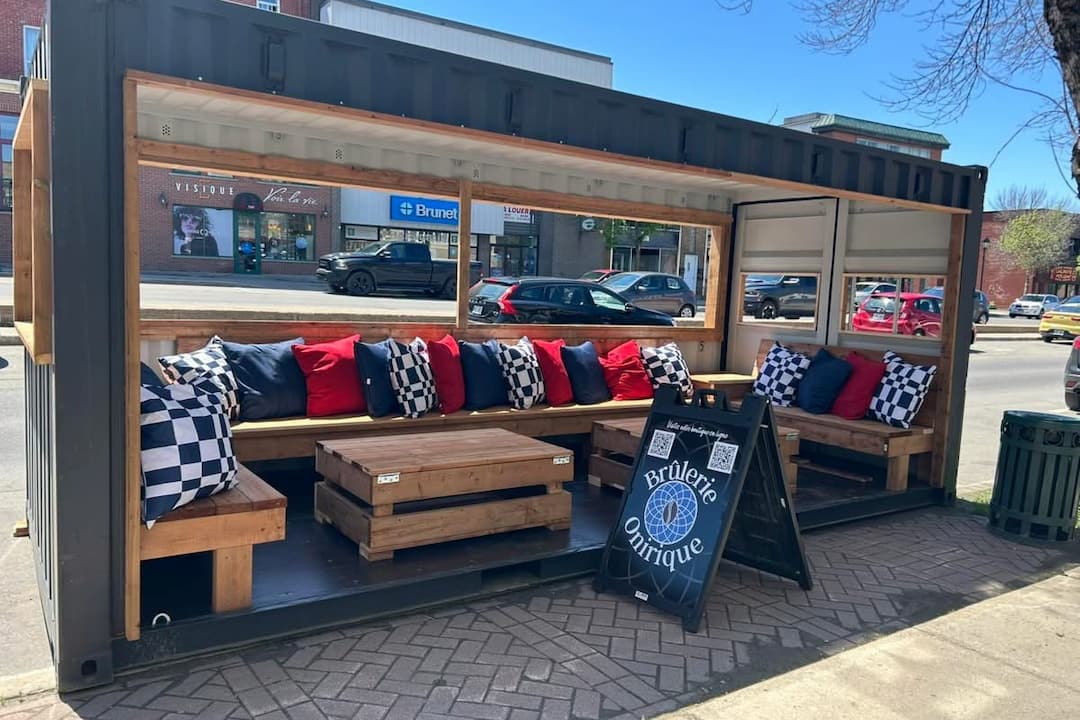 Terrasse extérieure de la Brûlerie Onirique, divans en bois avec coussins colorés